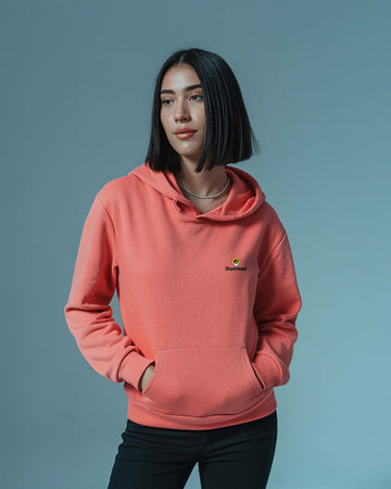 Person wearing a Dumkee pink hoodie with a logo on a gray background