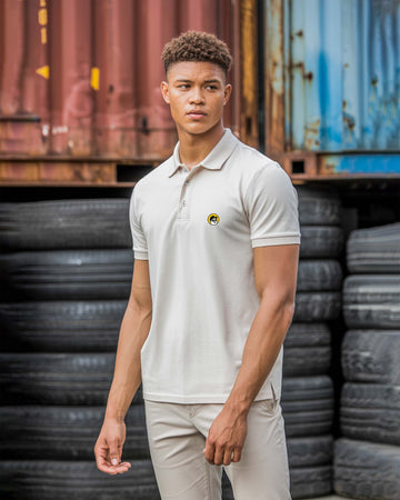 Person wearing a Dumkee light-colored polo shirt with a logo