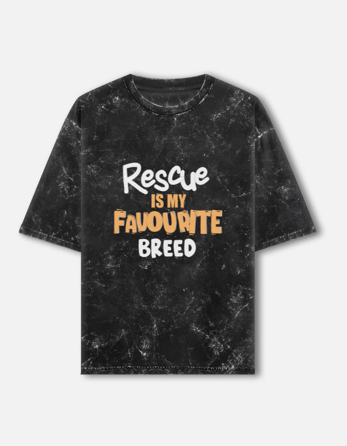 Man wearing a Dumkee Oversize black t-shirt with 'Rescue is my favourite breed' text in a park.