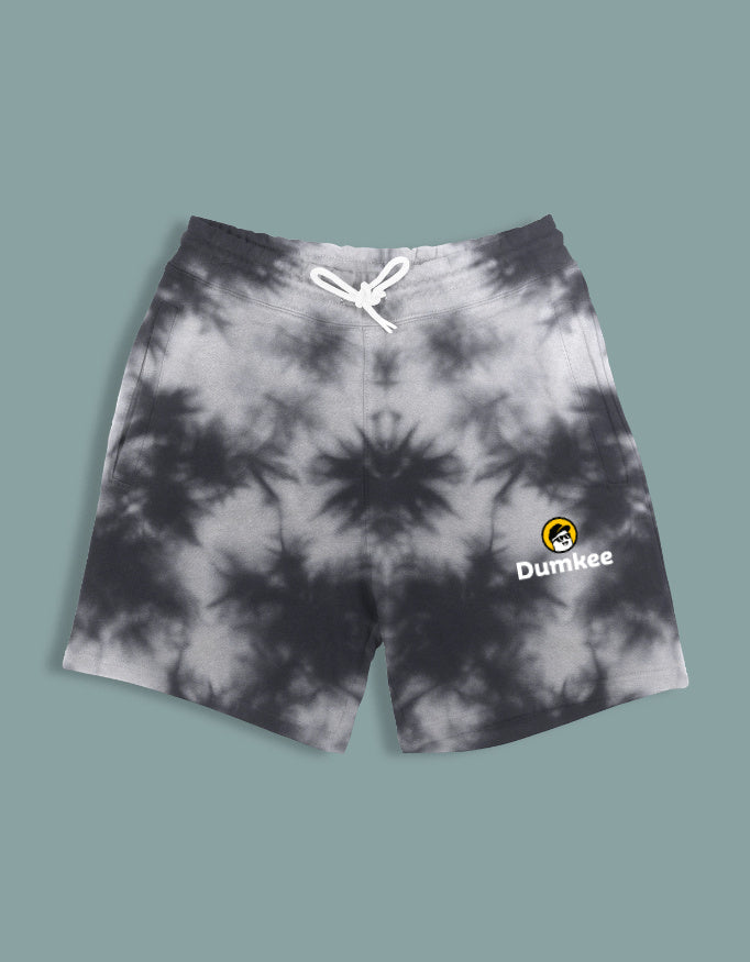 Person wearing Dumkee  tie-dye shorts with a brand logo on a plain background