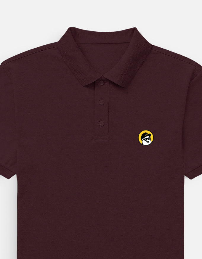 Man wearing a Dumkee maroon polo shirt with a yellow logo in an indoor setting