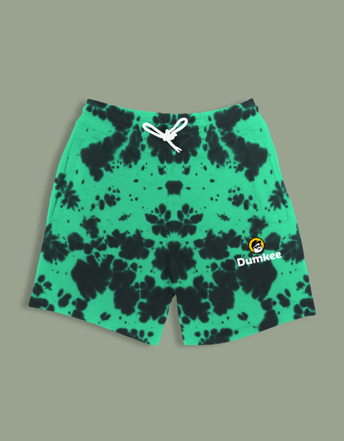 Green tie-dye Dumkee shorts with a brand logo worn by a person