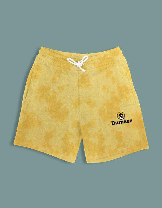 Person wearing Dumkee mustard yellow shorts with a brand logo