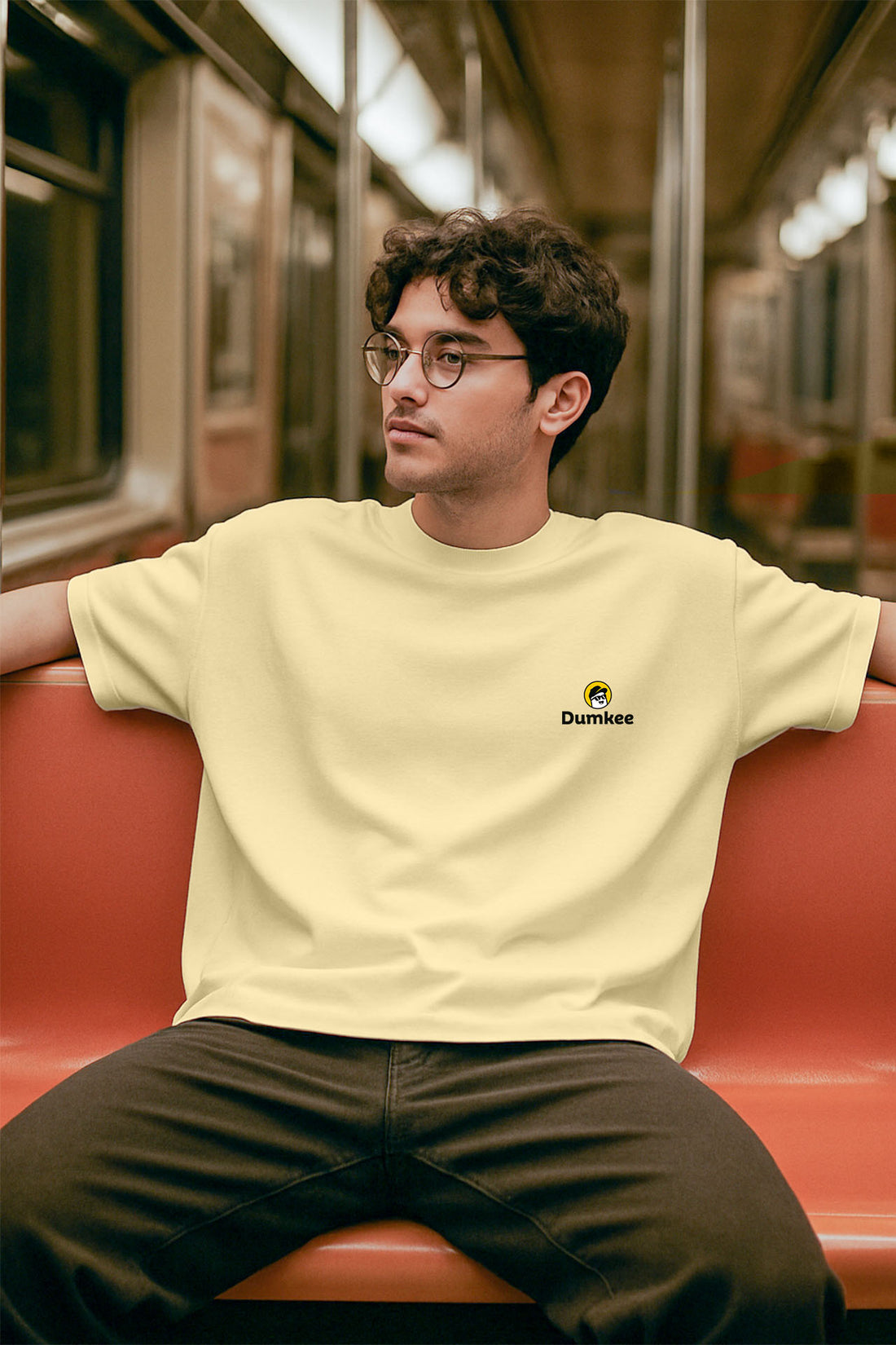 Person wearing a Dumkee Oversize light yellow t-shirt with a logo