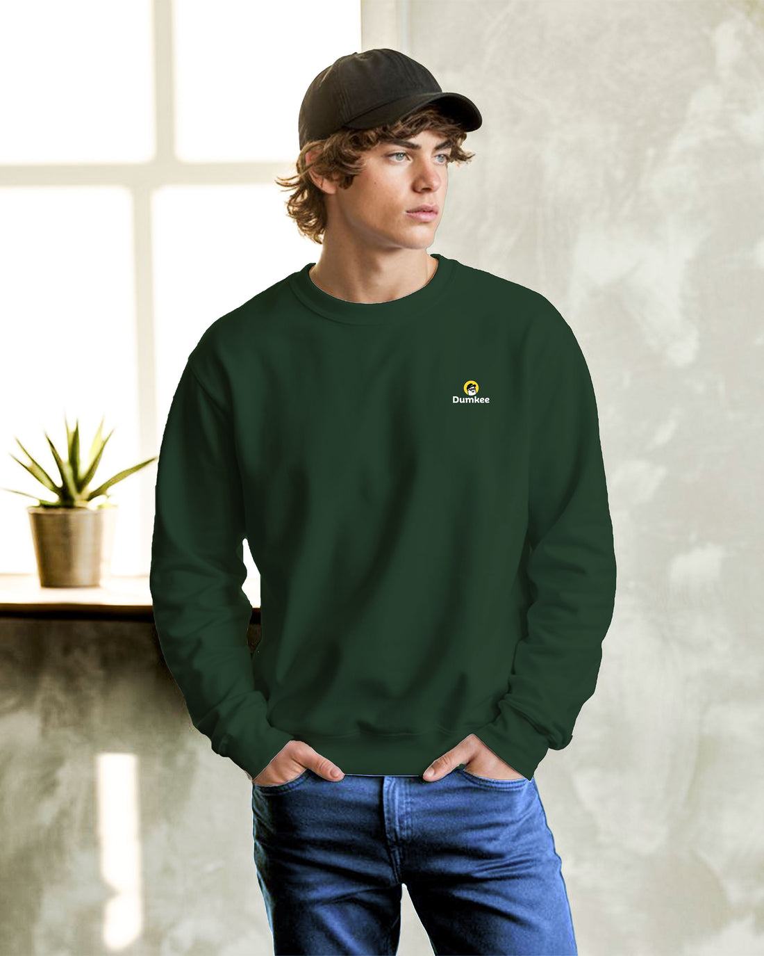Person wearing a Dumkee  bottle green sweatshirt with Dumkee logo.