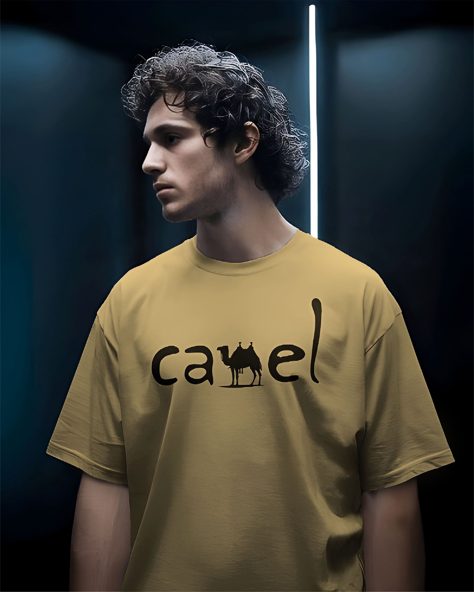 Person wearing a Dumkee Oversize yellow t-shirt with 'camel' logo against a dark background