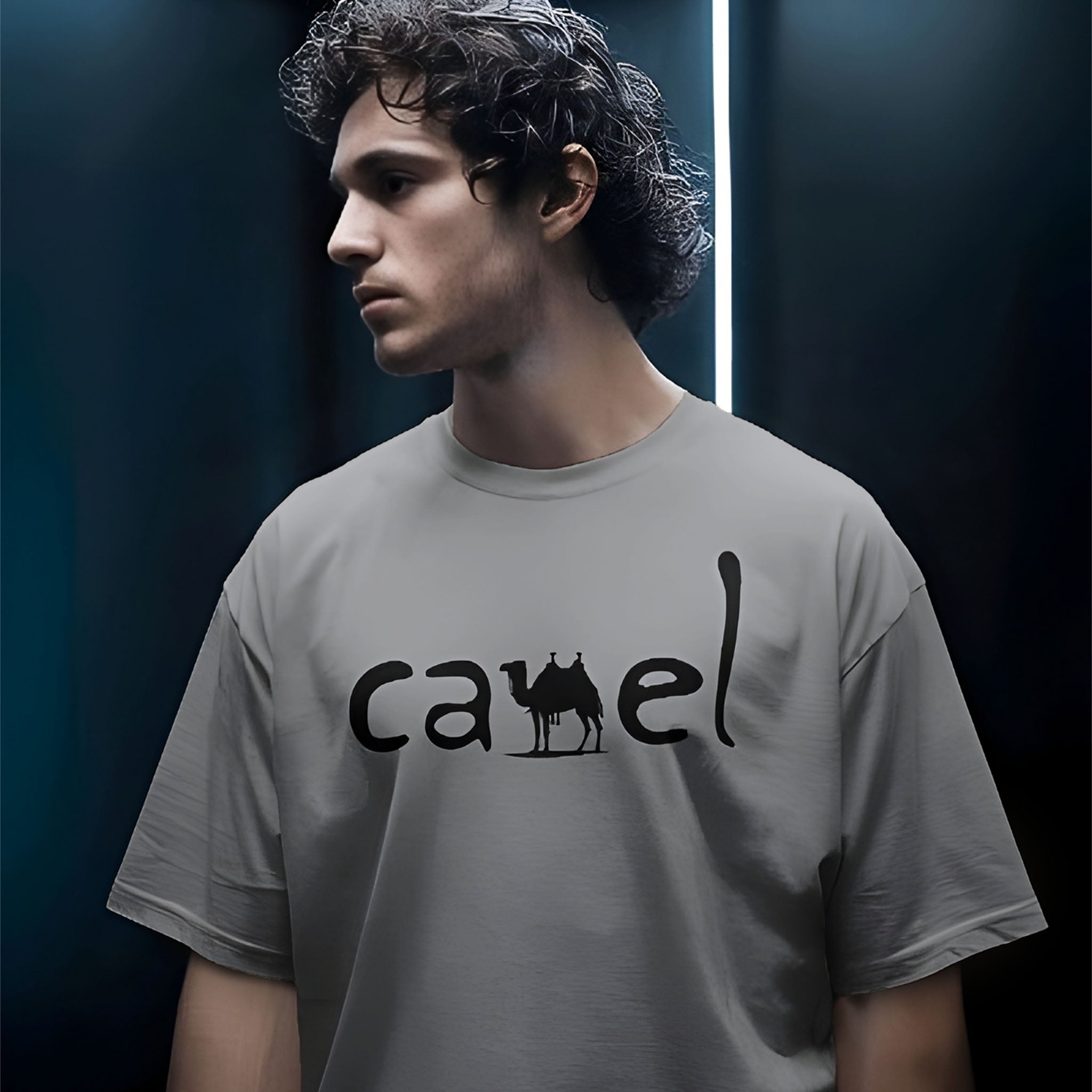 Person wearing a Dumkee Oversize gray t-shirt with 'camel' logo against a dark background