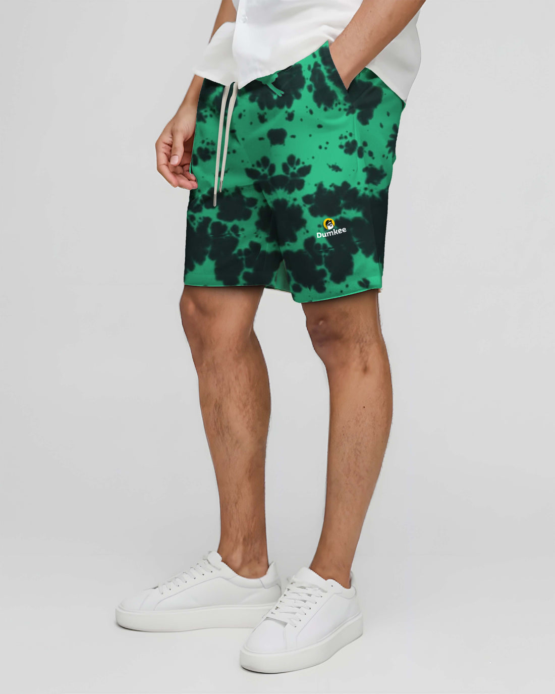 Green tie-dye Dumkee shorts with a brand logo worn by a person