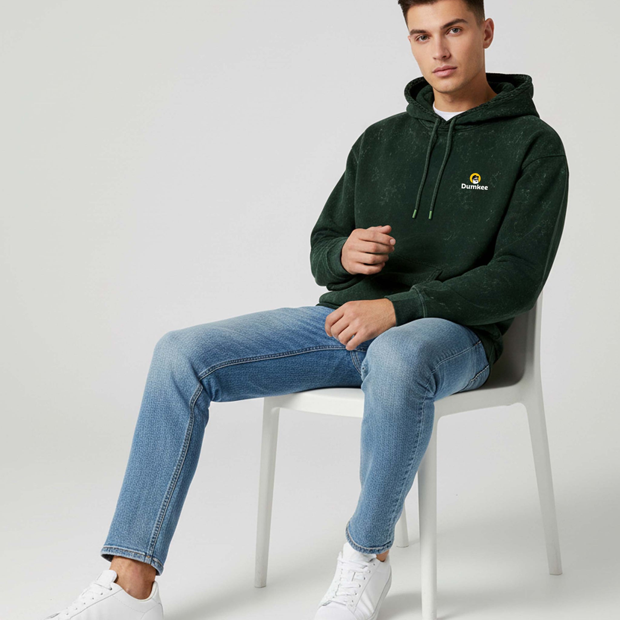 Man sitting on a Dumkee Oversize chair wearing a green hoodie