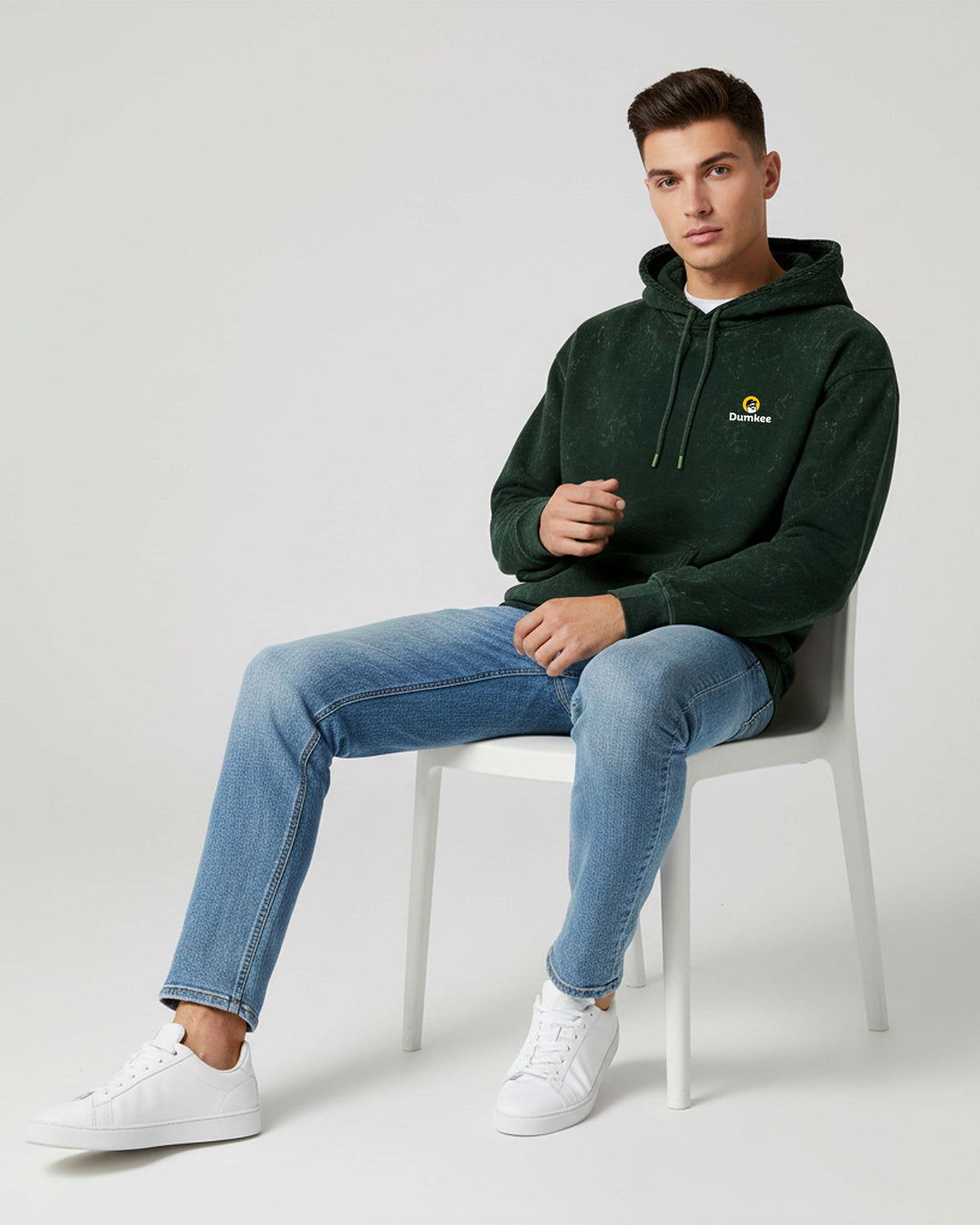 Man sitting on a Dumkee Oversize chair wearing a green hoodie