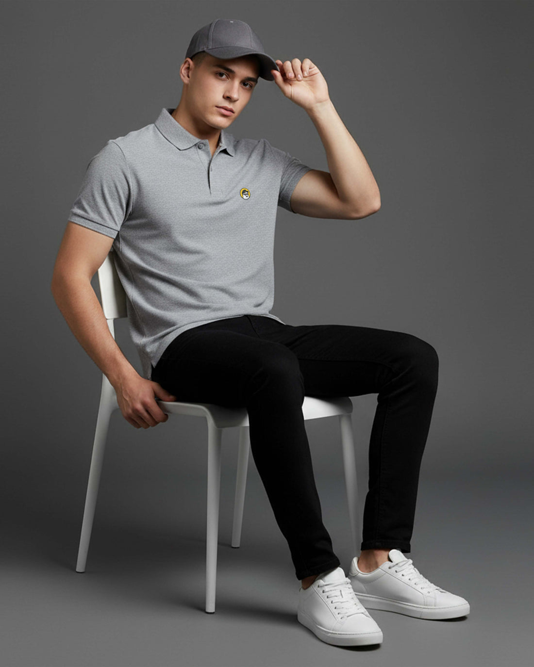 Man sitting on a chair wearing a Dumkee gray polo shirt