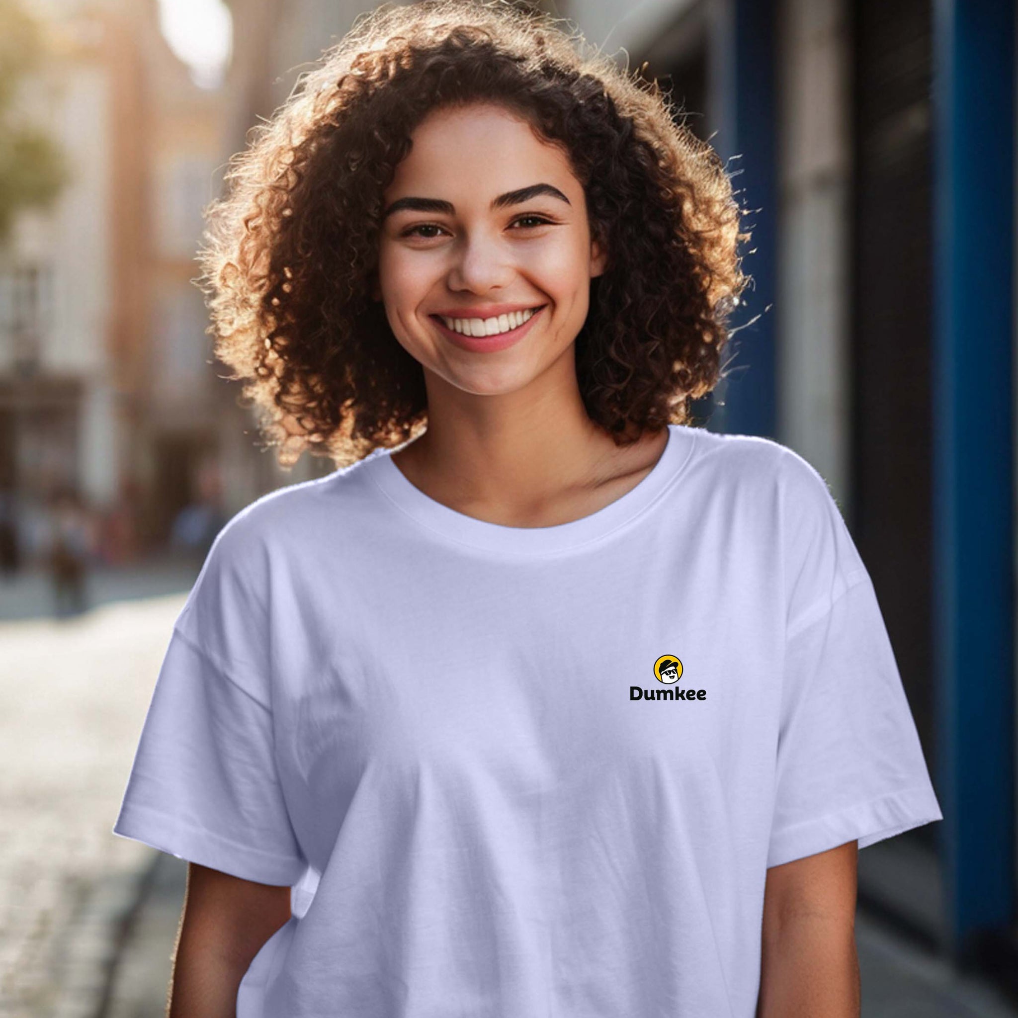 Person wearing a Dumkee Oversize white t-shirt with a Dumkee logo on a street.