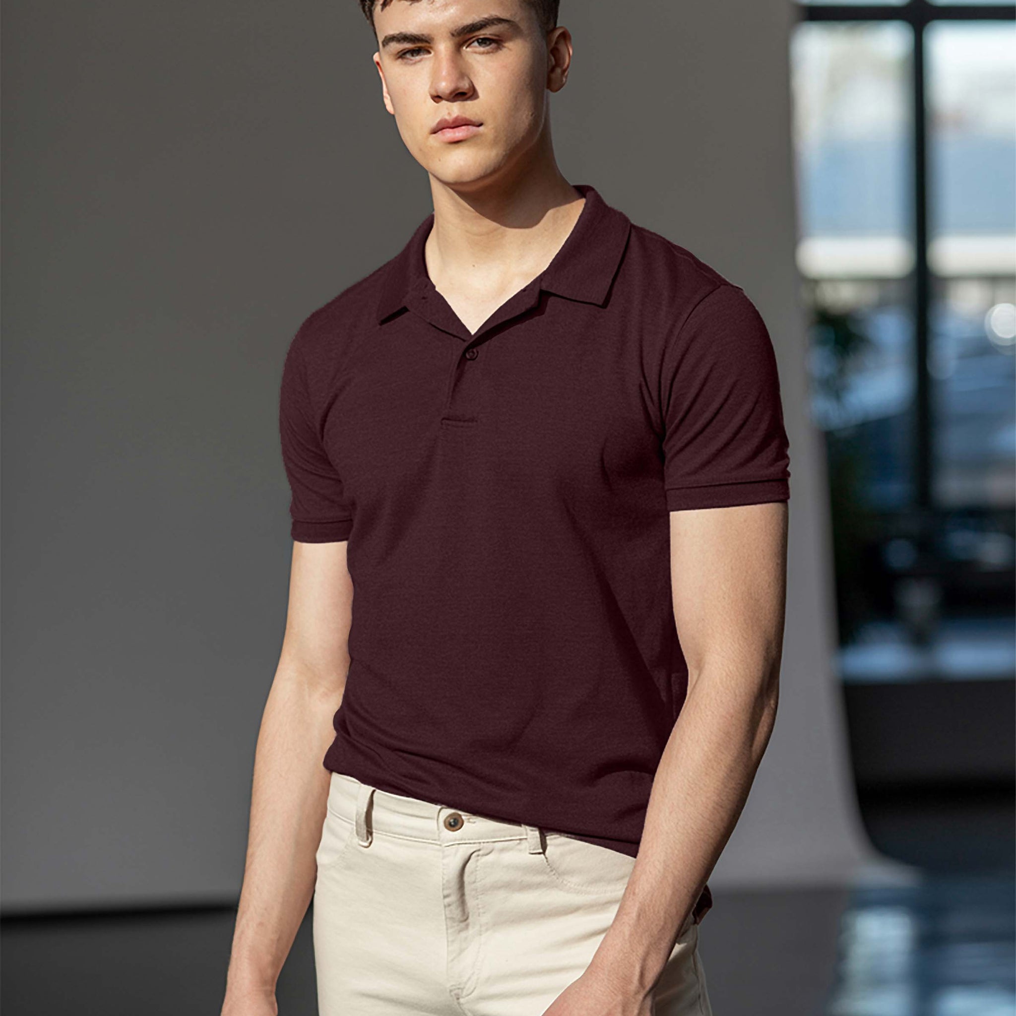 Man wearing a Dumkee  maroon polo shirt and beige pants