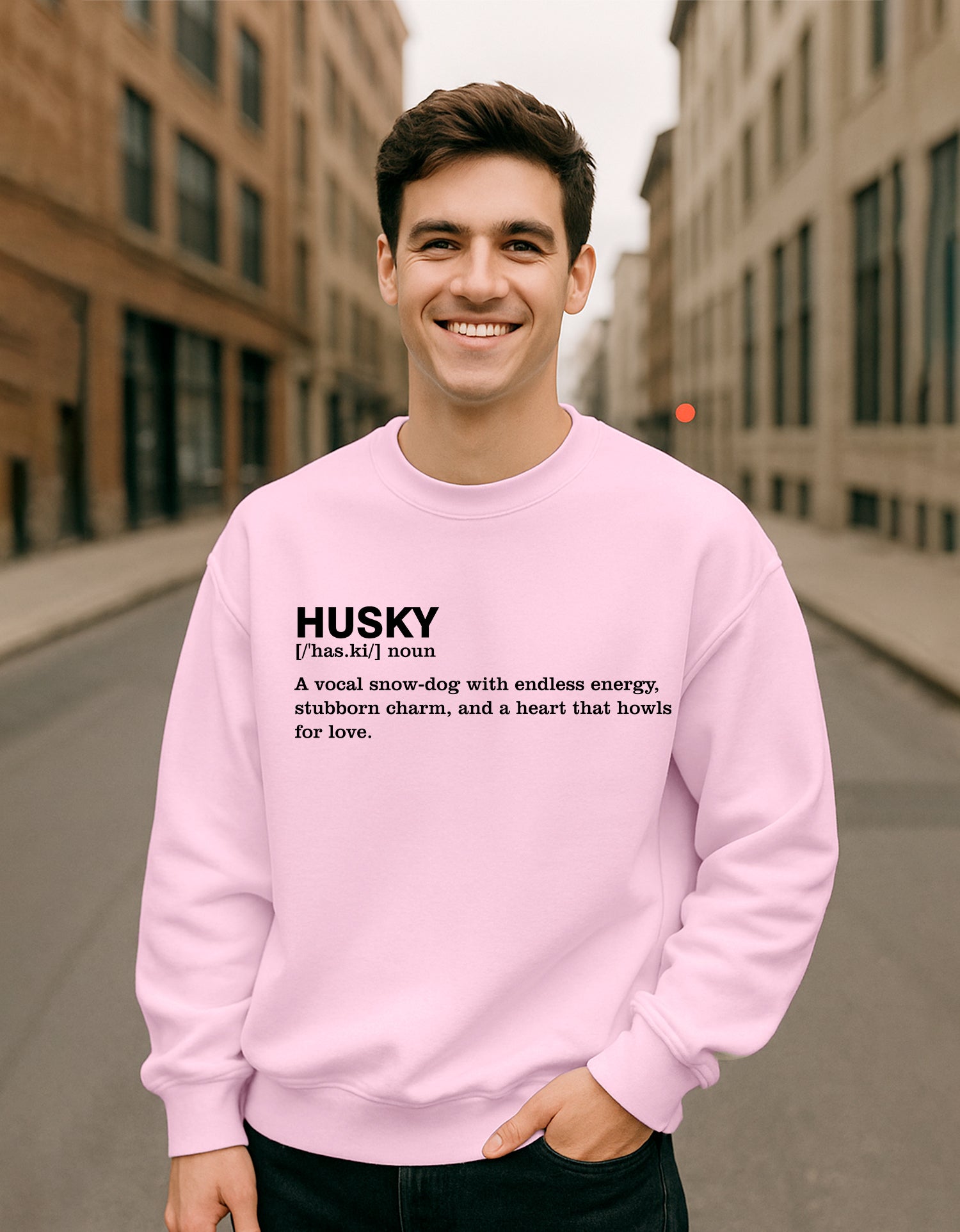 Person wearing a Dumkee Oversize pink sweatshirt with 'HUSKY' definition text on a city street.