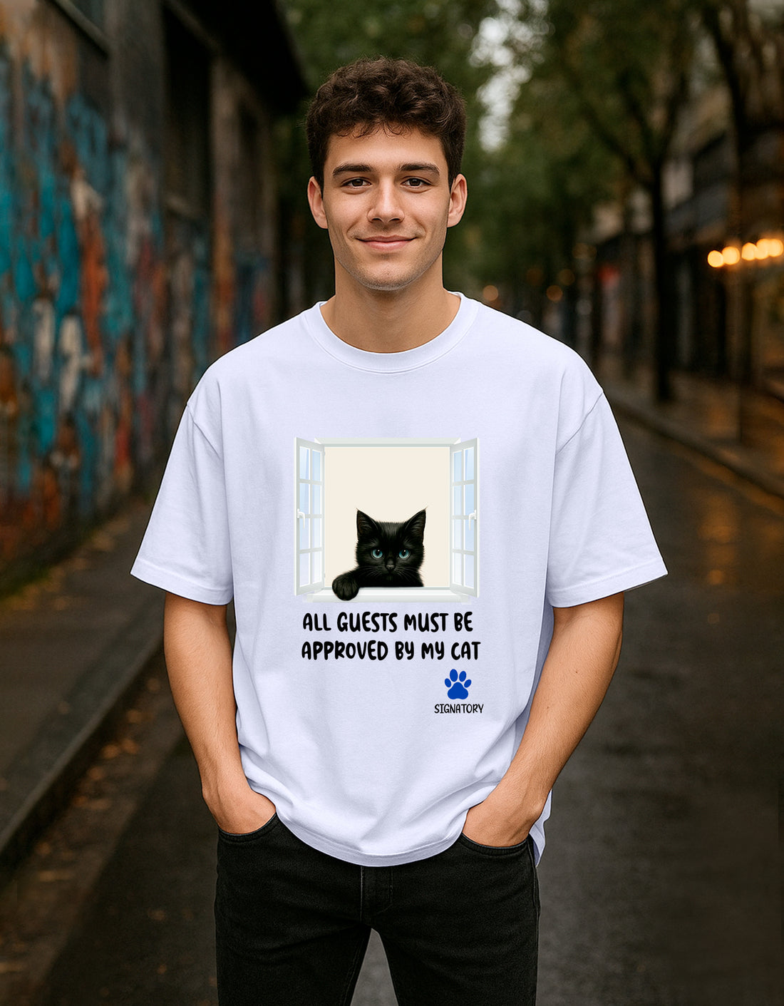 Person wearing a Dumkee white oversize t-shirt with a black cat graphic and text in an urban setting