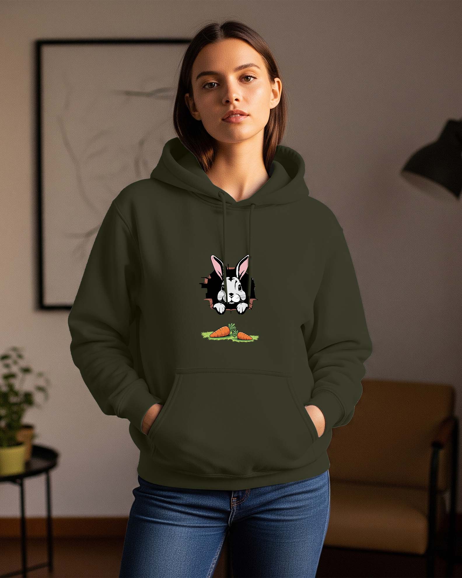 Woman wearing a Dumkee olive green regular fit  hoodie with a dog graphic in a room.