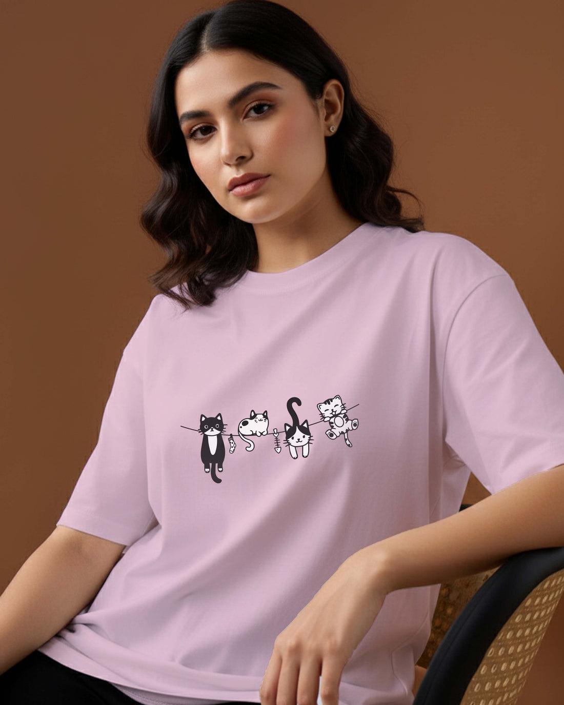 Woman wearing a Dumkee light purple oversize t-shirt with cat illustrations.