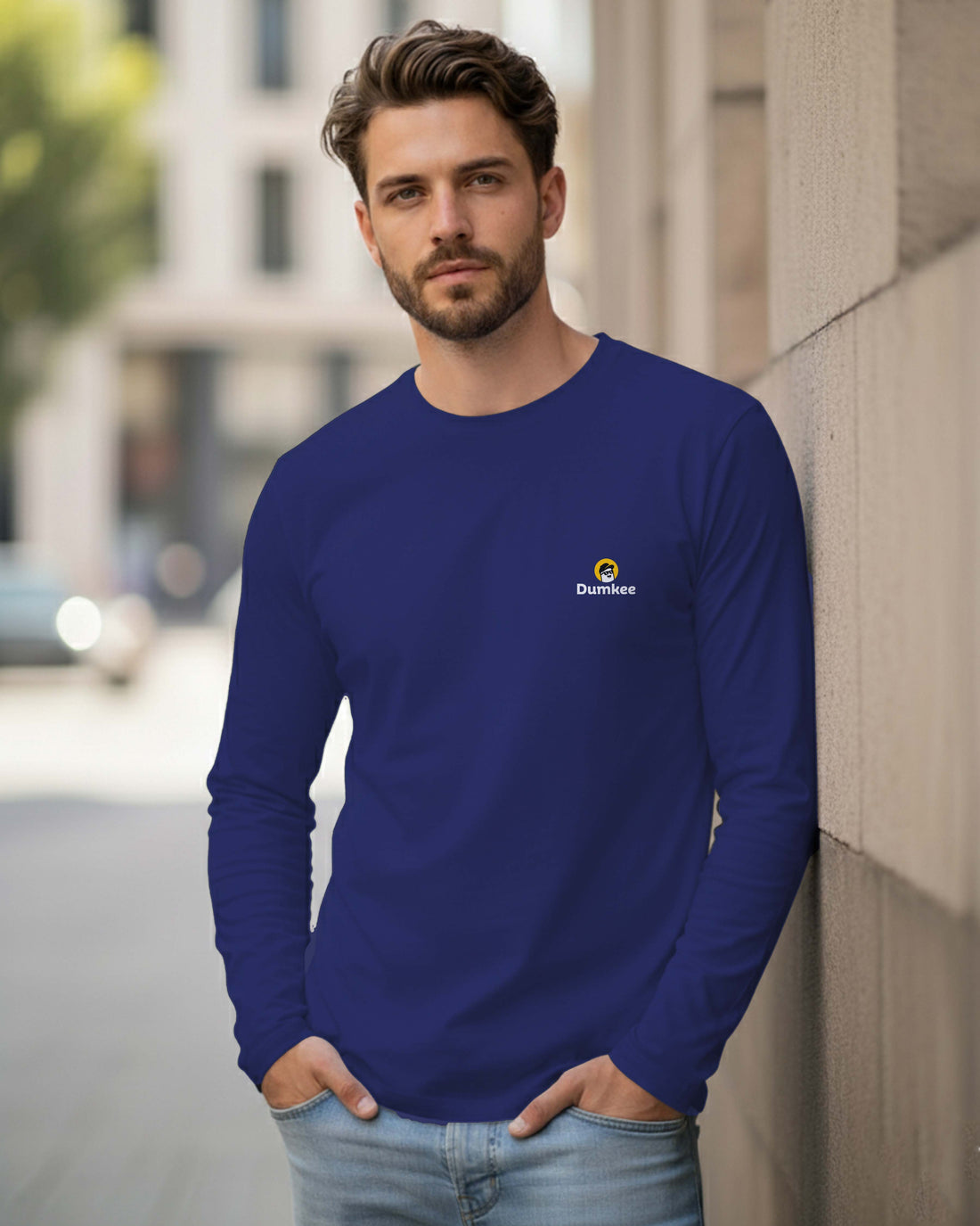 Man wearing a Dumkee blue long-sleeve shirt with a logo.