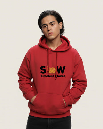 Person wearing a Dumkee Oversize red hoodie with 'SLOW Timeless Loves' text on a beige background