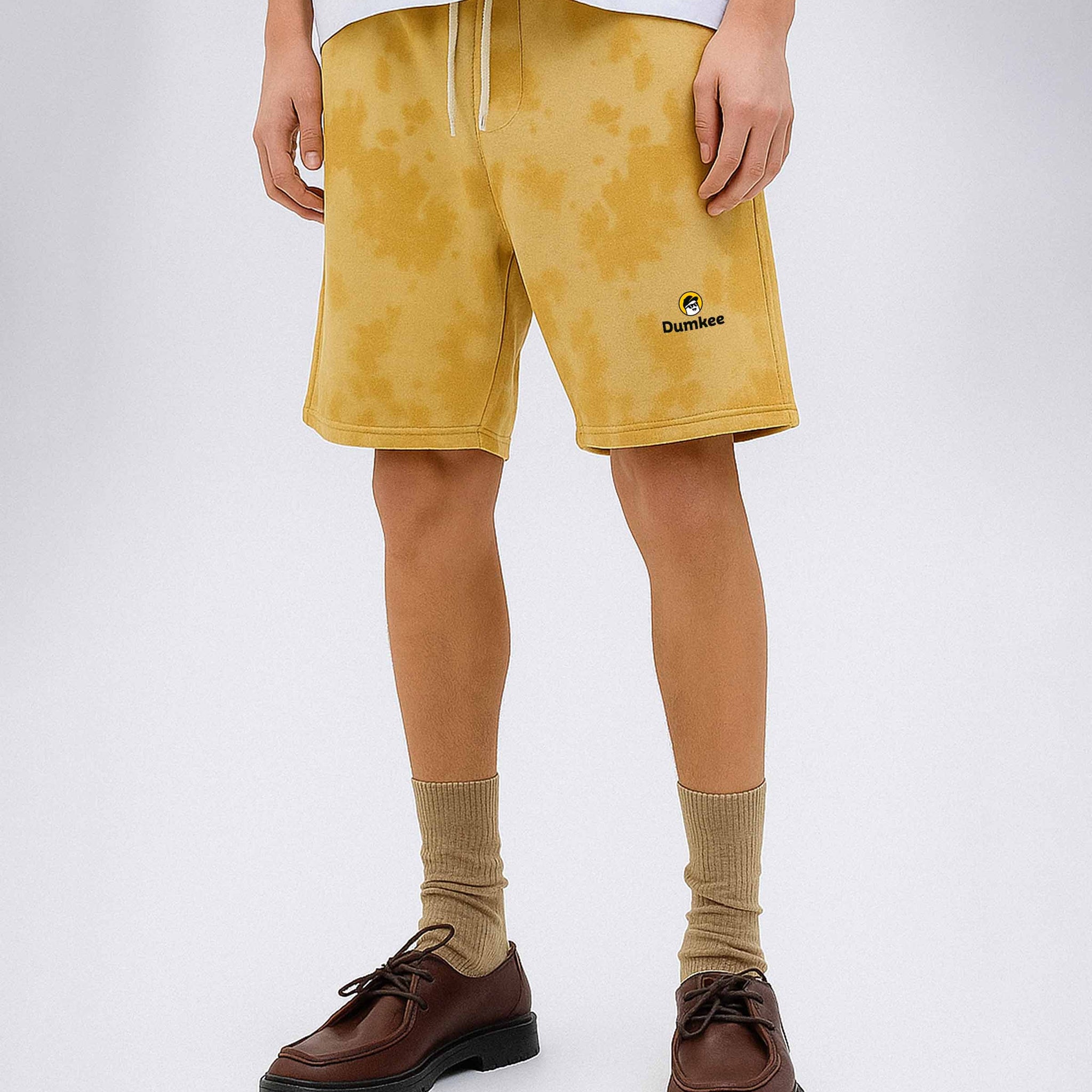 Person wearing Dumkee mustard yellow shorts with a brand logo