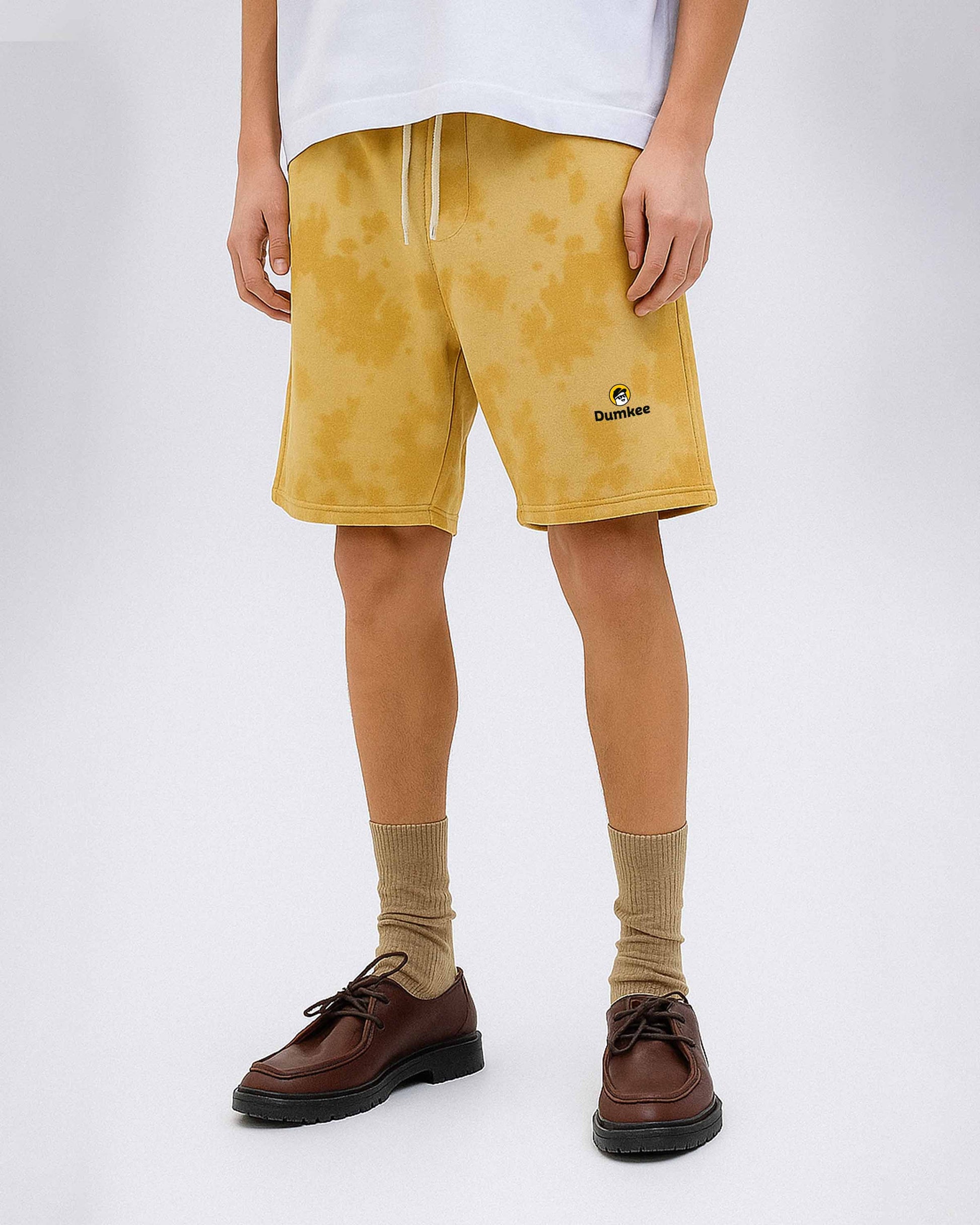 Person wearing Dumkee mustard yellow shorts with a brand logo